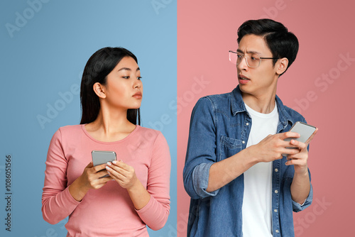 I want my privacy. Irritated asian guy doesnt like his girlfriend spying on him while using mobile phone, grey background photo