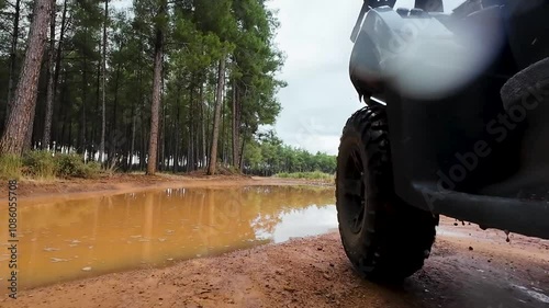 Offroad with an ATV in the forest, mud and puddles after the rain