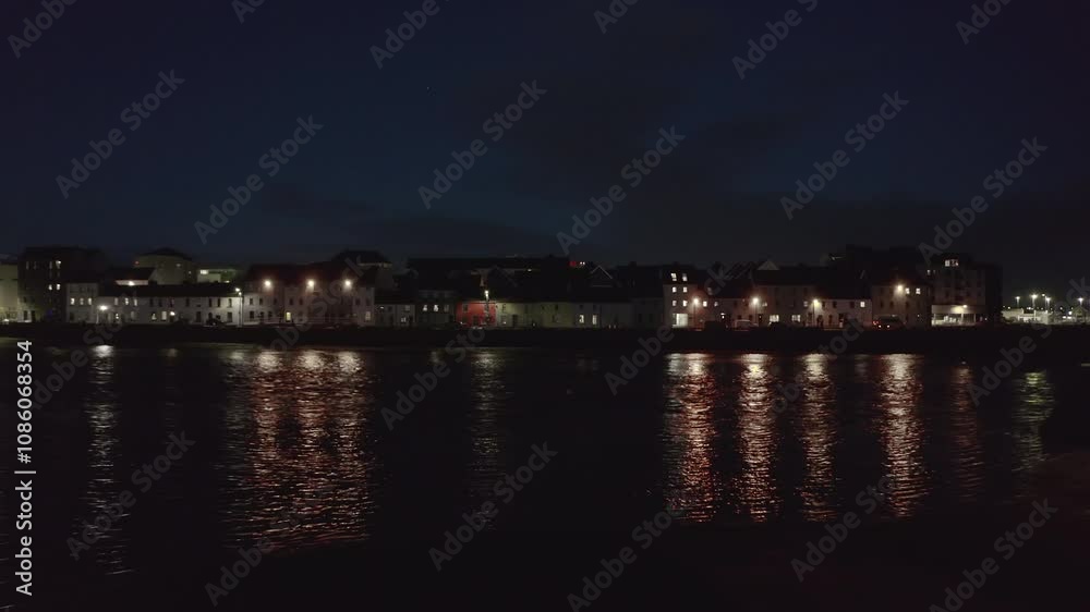 Night aerial pullback of Long Walk over water, revealing wide Galway city lights Night aerial pullback of Long Walk over water, revealing wide Galway city lights