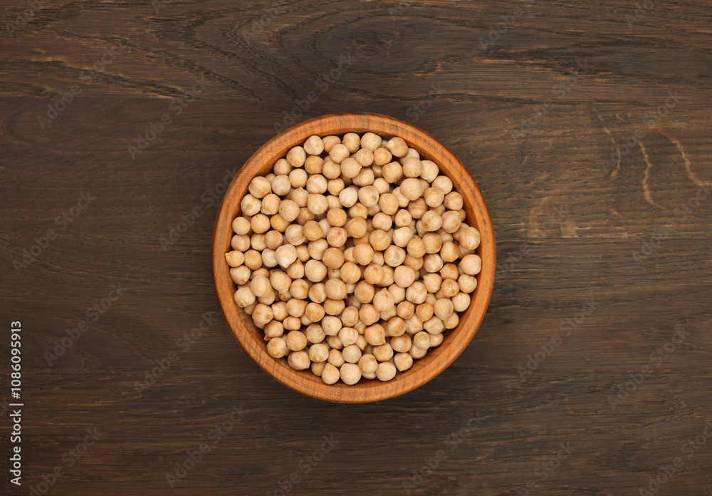 Chickpeas filling a wooden bowl on a dark wooden table Chickpeas filling a wooden bowl on a dark wooden table