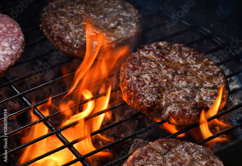 Quadro em tela Delicious hamburgers grilling on barbecue with flames