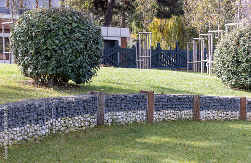 Garden arrangement landscaping. Mixture of natural garden arrangement. Building a wall with decorative stones using wire mesh for landscaping and design. photo