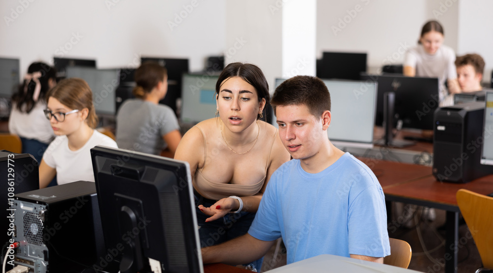 Teenager boy and girl studying in computer class, working on task solution together and using computer. Teenager boy and girl studying in computer class, working on task solution together and using computer.