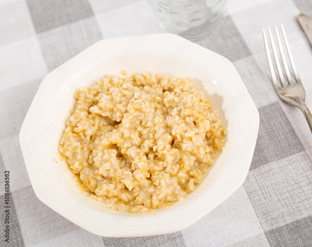 There is traditional breakfast on table - boiled milk oatmeal porridge, hearty and easy-to-prepare dish. There is traditional breakfast on table - boiled milk oatmeal porridge, hearty and easy-to-prepare dish.