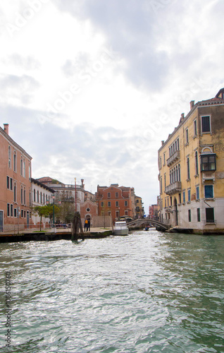 A view of historic Venetian buildings along the Grand Canal, showcasing classic Italian architecture. The iconic canal waters reflect the facades, with boats and gondolas adding to the charm of Venice