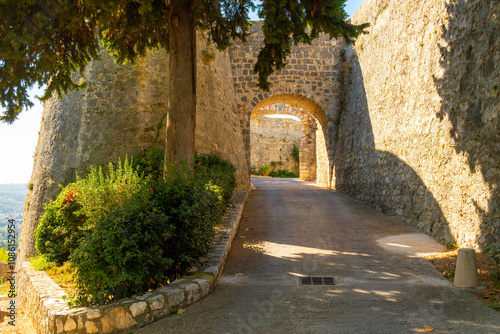 Fototapeta Naklejka Na Ścianę i Meble -  An arched stone passageway along the outer wall near Porte de Nice and Grignan Bastion in the walled medieval town of Saint Paul de Vence, France.