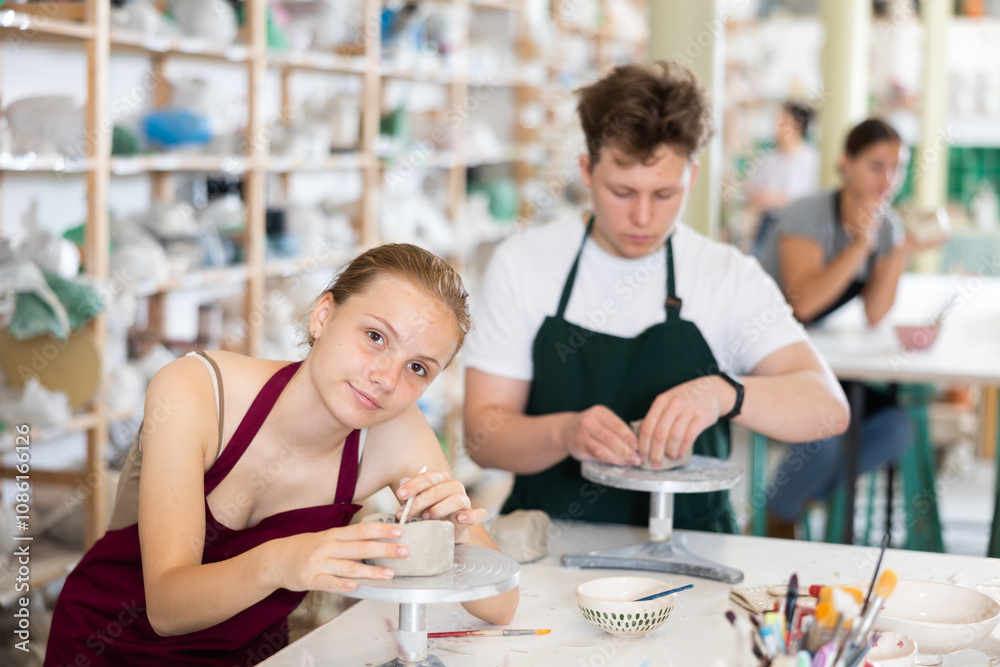 Students teenage girl and teenage boy sculpt ceramic product from raw clay in workshop Students teenage girl and teenage boy sculpt ceramic product from raw clay in workshop