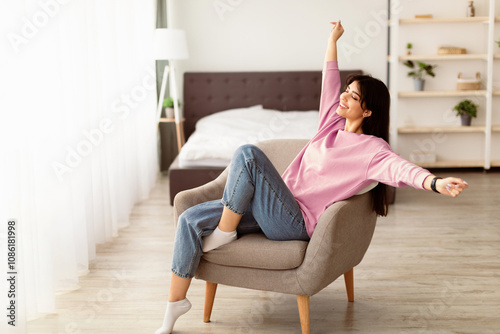 Weekend Recreation. Beautiful woman sitting on comfortable chair at home in living room, stretching arms. Happy lady relaxing with closed eyes, enjoying free time, taking break from work #1086181998