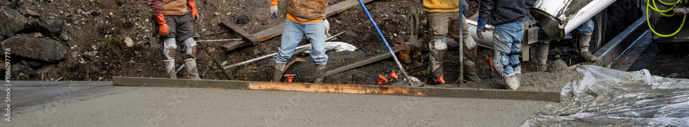 Construction workers finishing up a cement driveway paving project, cement truck delivering final load
Construction workers finishing up a cement driveway paving project, cement truck delivering final load