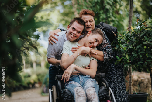 Foto A heartwarming scene of a boy with Down syndrome, a girl in a wheelchair, and an elderly woman sharing a joyful embrace outdoors among lush greenery
