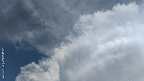 A towering cumulus cloud dominates the sky, its fluffy, white form contrasting against the deep blue backdrop. The image evokes a sense of wonder and the vastness of nature. photo