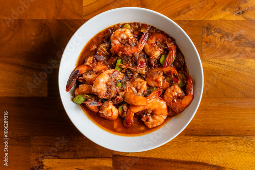 Spicy shrimp soup in a white bowl on a wooden table, udang balado,