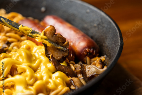 picking red smoked sausage as a topping in a home made ramen noodle photo