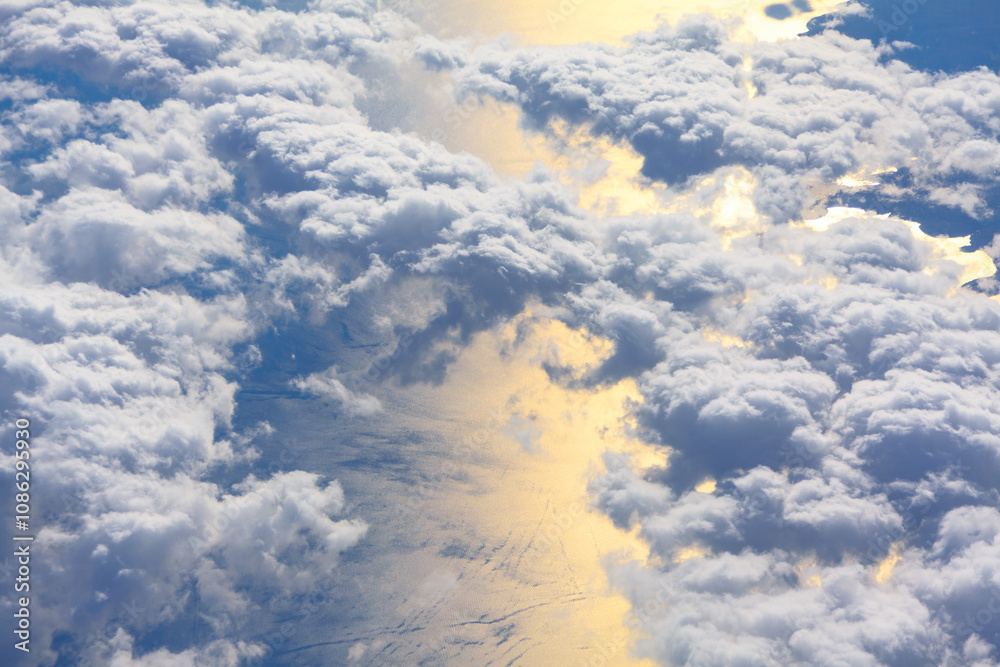Clouds are dense and fluffy, with sunlight reflecting off the surface of the sea water below. Vastness of the sky and the interplay of light and shadow on the clouds and water Clouds are dense and fluffy, with sunlight reflecting off the surface of the sea water below. Vastness of the sky and the interplay of light and shadow on the clouds and water