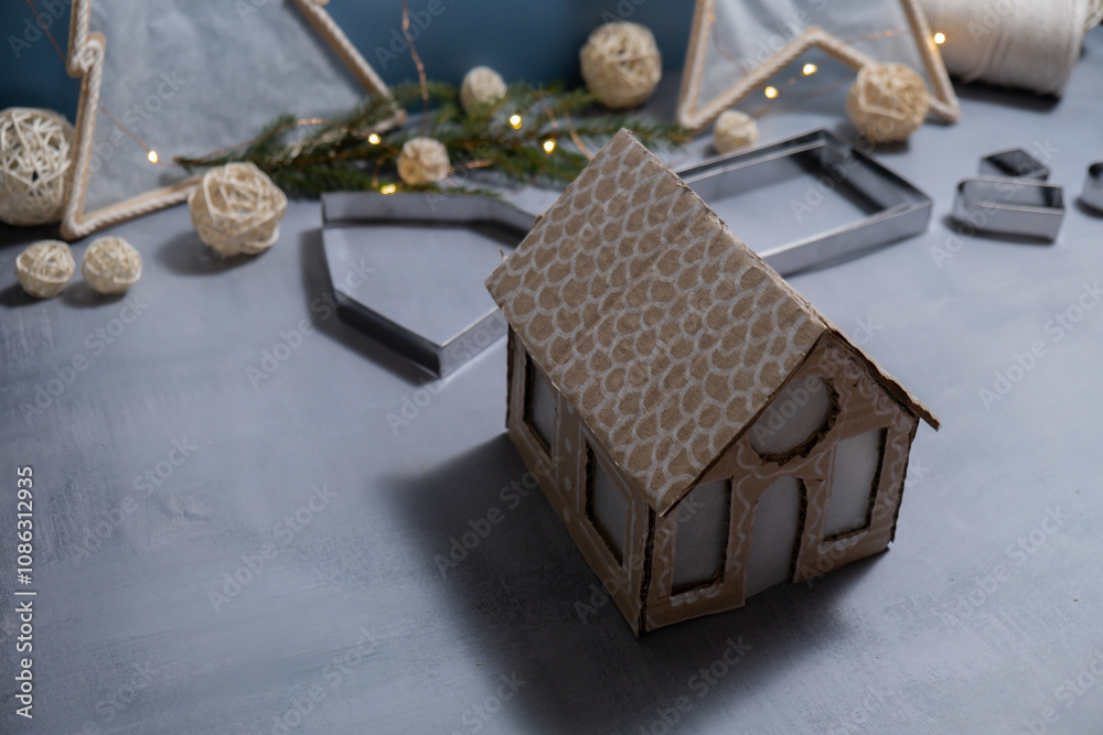 Fototapeta premium Cardboard House Gift Christmas idea. Do it yourself instruction eco-friendly decoration. Zero waste Making handmade presents children's diy projects. Holiday family time