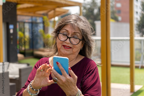 Portrait of a senior woman with glasses using her cell phone outdoors