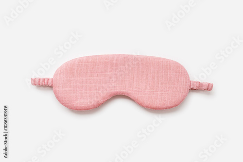 Sleeping mask for healthy quality sleep on white light background. One pink colored eye mask for best sleeps. Stylish silk eye cover or blindfold for travel, comfort rest, minimal top view photo