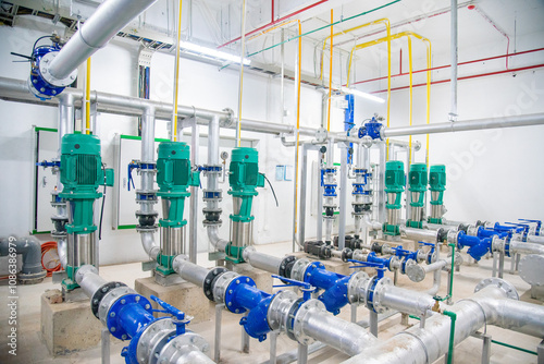 Industrial interior of water pump, valves, pressure gauges, motors inside engine room. Valve and pumps in an industrial room. Urban modern powerful pipelines and pumps, automatic control systems