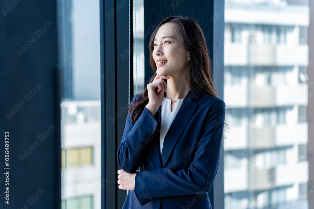 外を見つめるスーツを着た若い日本人女性 外を見つめるスーツを着た若い日本人女性