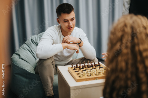 A group of teenagers engage in a friendly chess game indoors, focusing on strategy and concentration in a casual environment. Perfect for themes of leisure, youth, and strategic thinking. photo