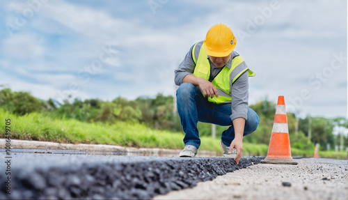 Construction worker reviewing new asphalt layer on roadwork site