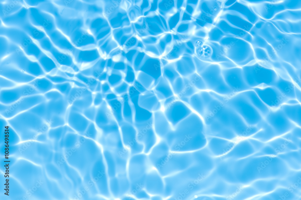 Obraz premium Blue water with ripples on the surface. Defocus blurred transparent blue colored clear calm water surface texture with splashes and bubbles. Water waves with shining pattern texture background.