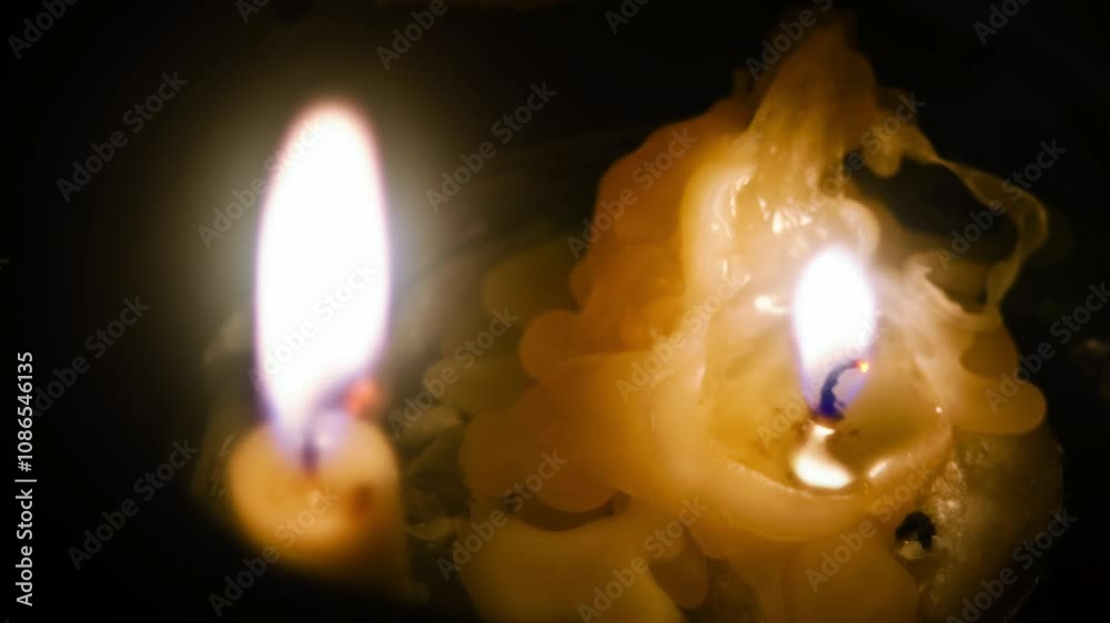 Closeup time-lapse footage of two lighted candles melting on a stainless plate