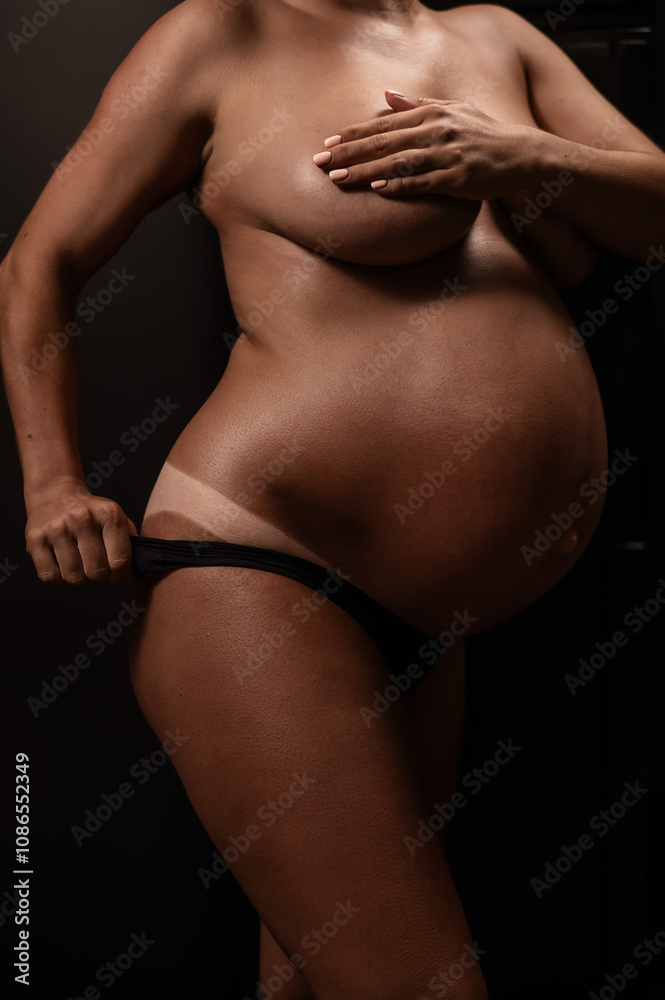 Naklejka premium Pregnant woman pulls back her panties showing instant tan. Vertical photo. 