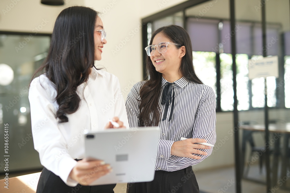 Happy Asian business people working together using laptop and tablet in office. Happy Asian business people working together using laptop and tablet in office.