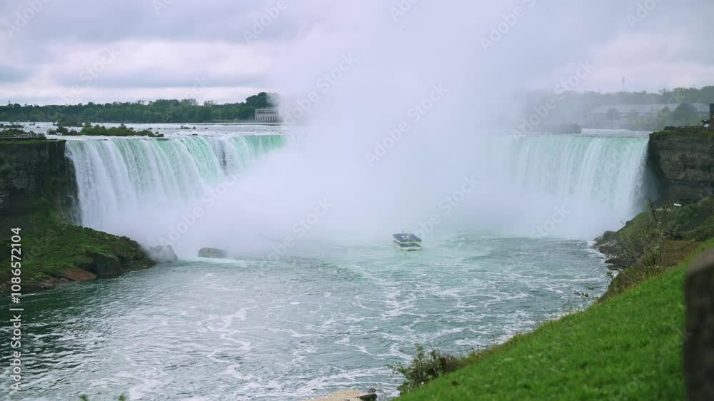Panoramic view of majestic Niagara Falls, with tour boat approaching cascading water amidst misty and lush environment, highlighting grandeur of nature. Niagara Falls tour boat Niagara Falls panoramic