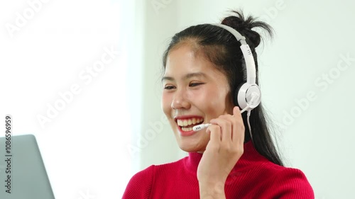 A businesswoman sits at her desk, smiling while talking on the phone and looking at her laptop. She focuses on analyzing tasks, planning strategies, and engaging in productive online discussions.