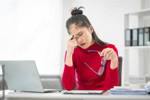 Canvas Print A businesswoman sits at her desk, stressed and anxious while looking at her laptop