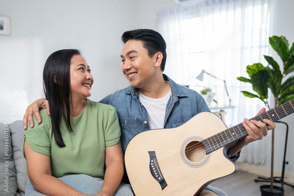 © Kawee - Asian couple spending free leisure time together in living room in house.