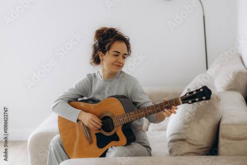 A woman learns to play the guitar at home