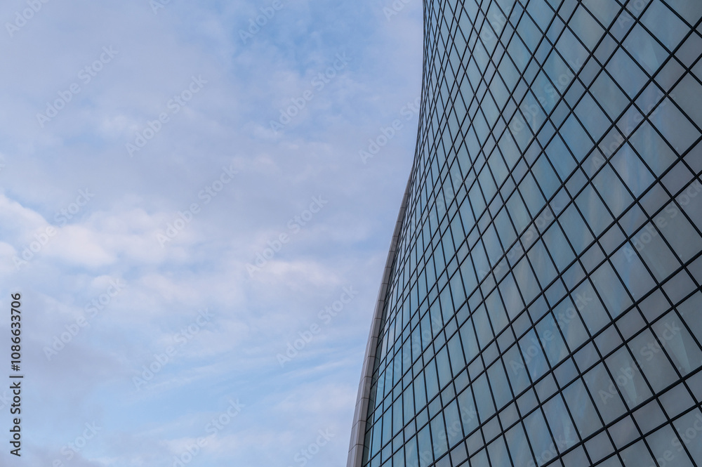 Windows of building at sunset. Reflection of the sky in the window glass. Skyscrapers in business district against blue sky. Looking up high-rise office buildings. Angled view. Windows of building at sunset. Reflection of the sky in the window glass. Skyscrapers in business district against blue sky. Looking up high-rise office buildings. Angled view.