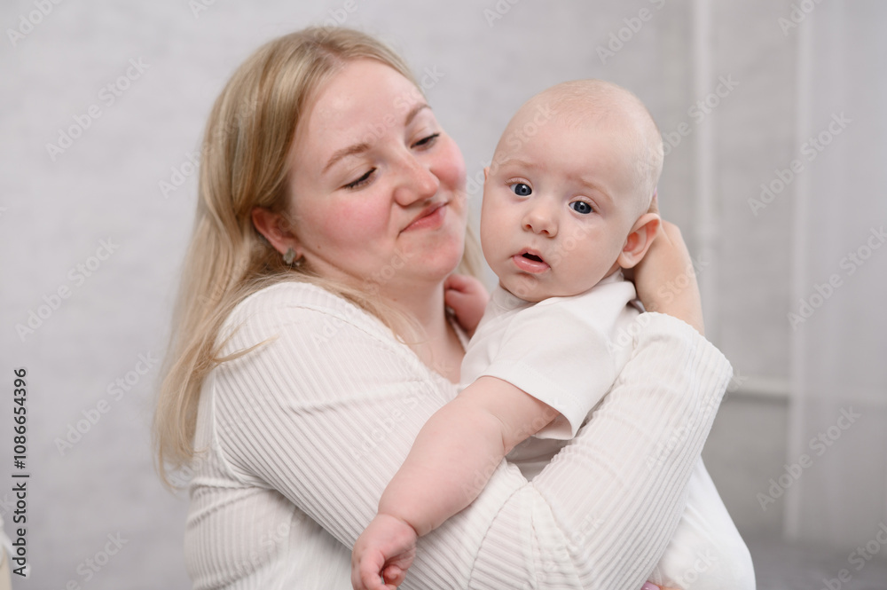 Happy mother holds her baby in an upright position, helps remove air from stomach after feeding, rocking. Woman enjoys tender moment, caring for infant. Concepts of motherhood and tenderness.Vertical Happy mother holds her baby in an upright position, helps remove air from stomach after feeding, rocking. Woman enjoys tender moment, caring for infant. Concepts of motherhood and tenderness.Vertical