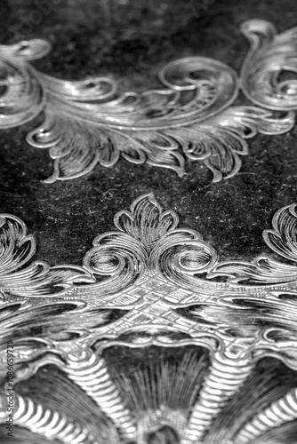 Engraving pattern background on an antique silver plate pewter tray.  Antique vintage metalwork concept.