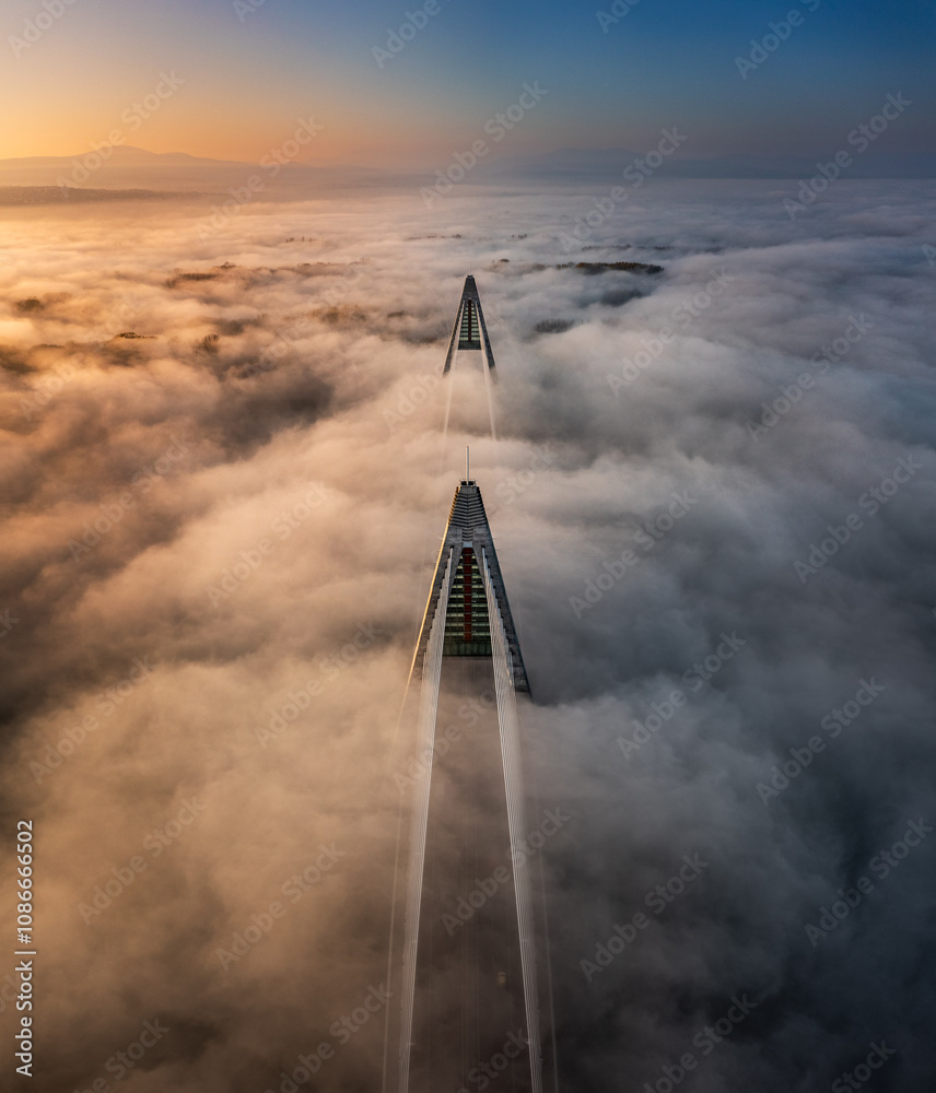 Budapest, Hungary - Aerial panoramic view of Megyeri Bridge over River Danube on a foggy autumn afternoon with beautiful gold and blue sky at sunset