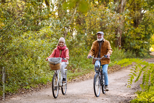 Beautiful elderly couple on bike ride in the forest. Seniors in love cycling through autumn nature, enjoying a peaceful moment.