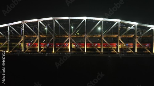 Aerial night view of Malviya Bridge, Varanasi, India, July 2024. A train crosses the Ganga River near the illuminated ghats, including Namo Ghat, in this stunning dolly-out shot over Rajghat. photo