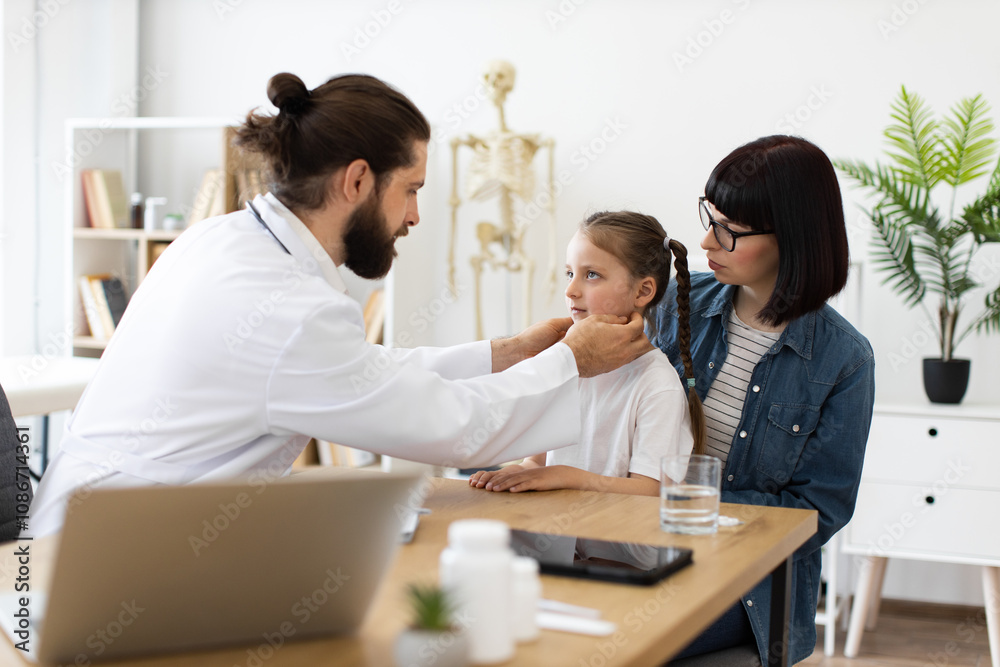 Experienced male doctor examines lymph nodes of Caucasian girl while Caucasian mother sits nearby. Scene in modern clinic setting demonstrates healthcare, care, trust, and pediatric consultation. Experienced male doctor examines lymph nodes of Caucasian girl while Caucasian mother sits nearby. Scene in modern clinic setting demonstrates healthcare, care, trust, and pediatric consultation.