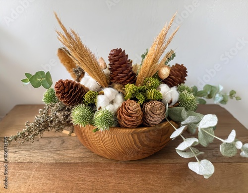 Decorative composition featuring pine cones, cotton flowers, and dried plants in wooden bowl photo