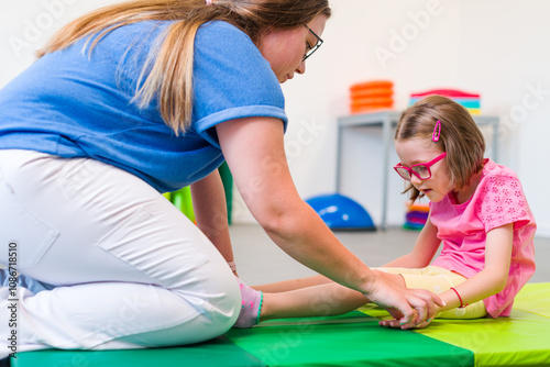 Child with physical disability in physical therapy session. Child living with cerebral palsy exercising with her therapist during physiotherapy.