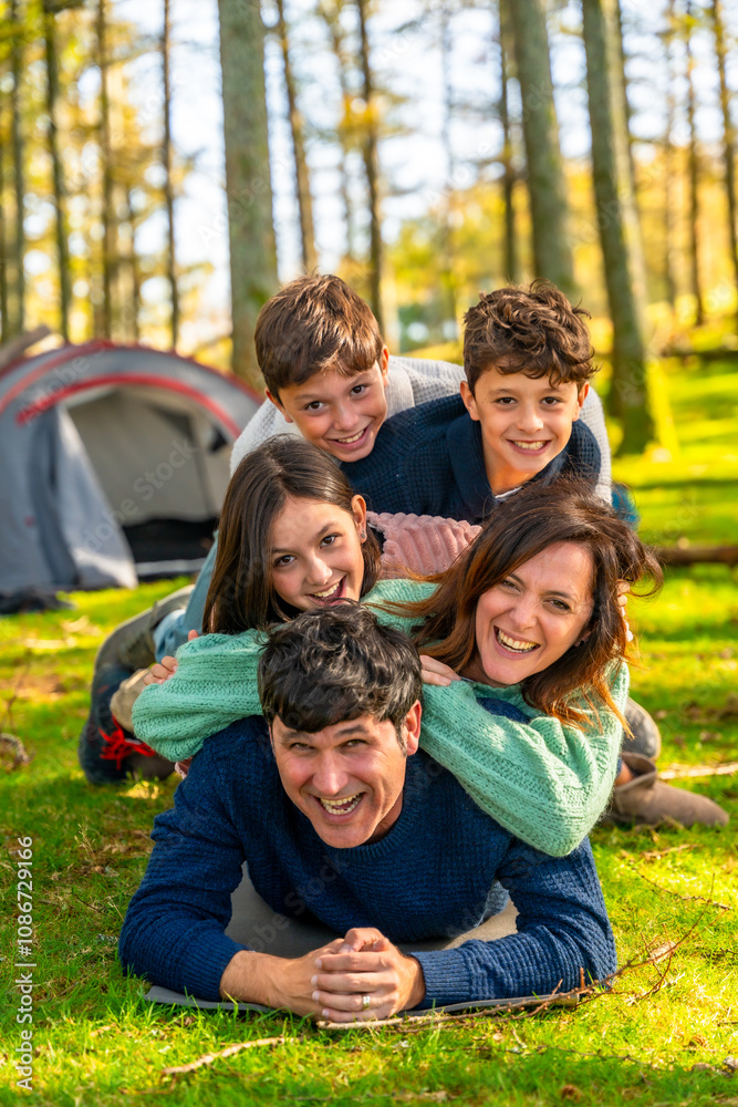 Cheerful family laughing while lying down together at forest Cheerful family laughing while lying down together at forest