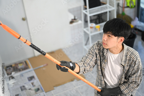 Concentrated young man painting the wall with a roller