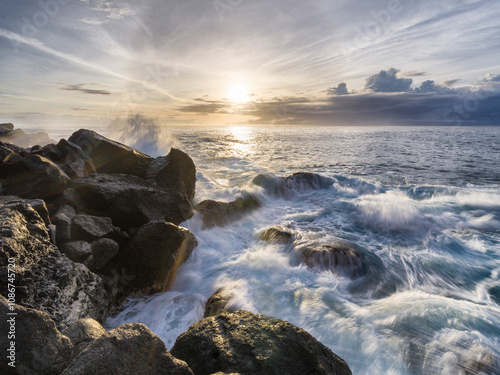Waves crashing against rocky shoreline during sunset in the Azores Islands creating a peaceful coastal view