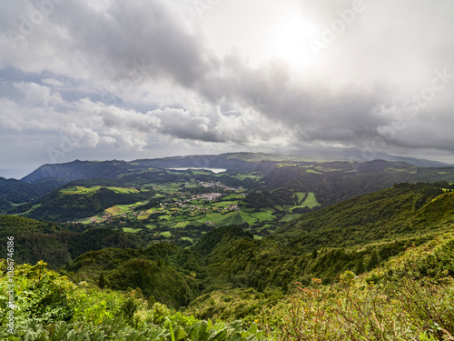 A stunning view of Sao Miguel Island features lush hills and valleys beneath a cloudy sky, showcasing its natural beauty.