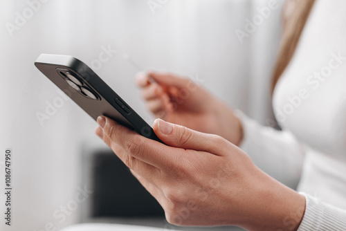 Close up of woman hands holding credit card and smartphone, young female paying online, using banking service, entering information, shopping, ordering in internet store, girl doing secure payment