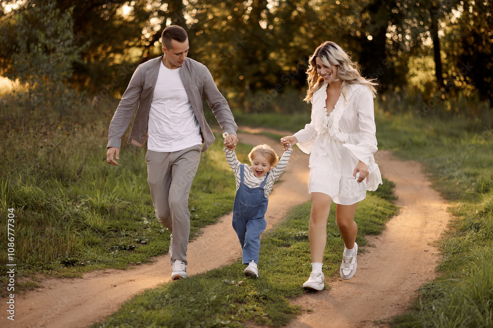 Fototapeta premium Happy family walking on the grass in the summer park. Mother father and children playing in nature. Children Protection Day. 