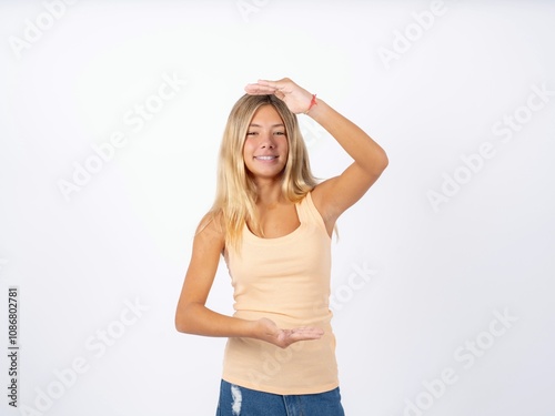 Beautiful teen girl wearing sleeveless t-shirt gesturing with hands showing big and large size sign, measure symbol. Smiling looking at the camera.